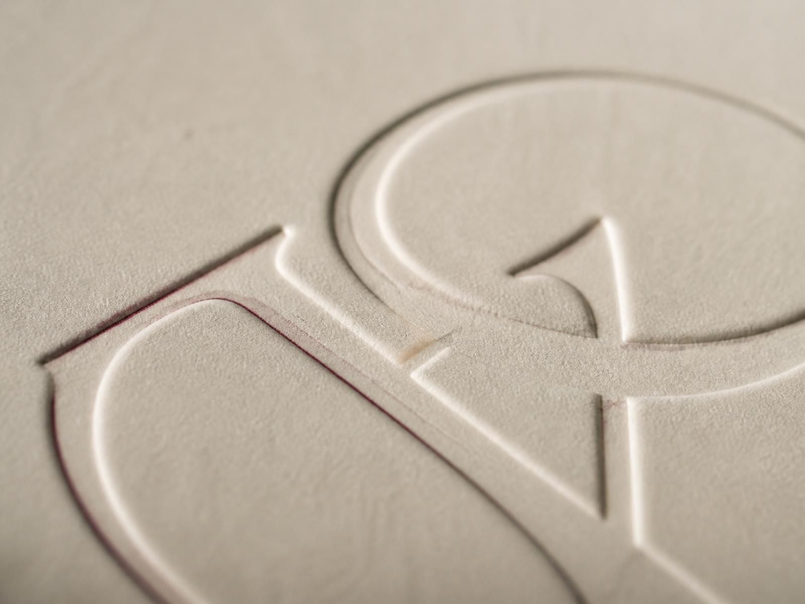 Macro detail of a blind-embossed monogram on thick cotton paper